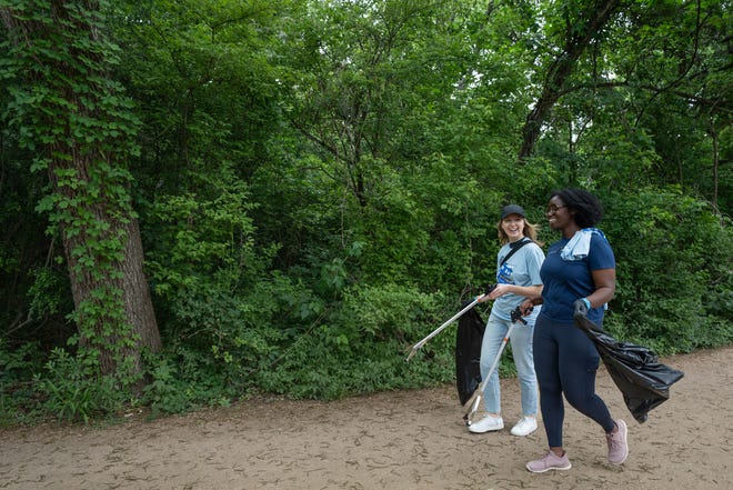 Becca Johnson and Chelsea Quayenortey look for trash along Butler Hike-and-Bike Trail for Earth Day Cleanup for The Trail Conservancy on Friday, April 19, 2024. Volunteers spent the day cleaning up Butler Hike-and-Bike Trail and Lady Bird Lake.