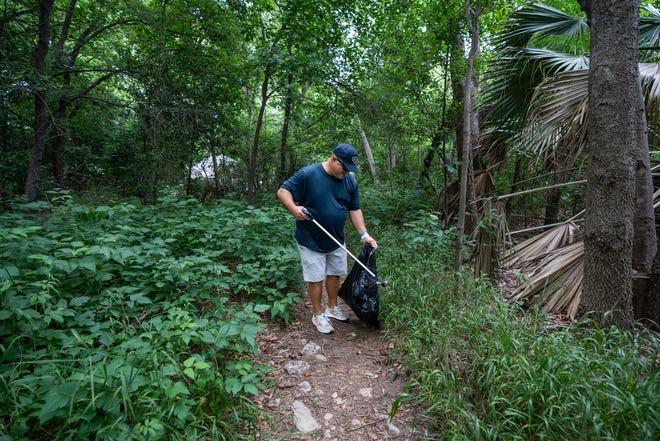 Derek Horton looks for trash along Butler Hike-and-Bike Trail for Earth Day Cleanup for The Trail Conservancy on Friday, April 19, 2024. Volunteers spent the day cleaning up Butler Hike-and-Bike Trail and Lady Bird Lake.