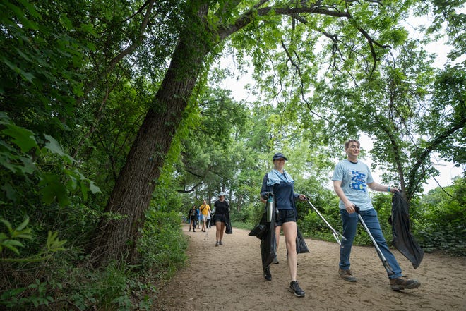 Volunteers look for trash along Butler Hike-and-Bike Trail for Earth Day Cleanup for The Trail Conservancy on Friday, April 19, 2024. Volunteers spent the day cleaning up Butler Hike-and-Bike Trail and Lady Bird Lake.